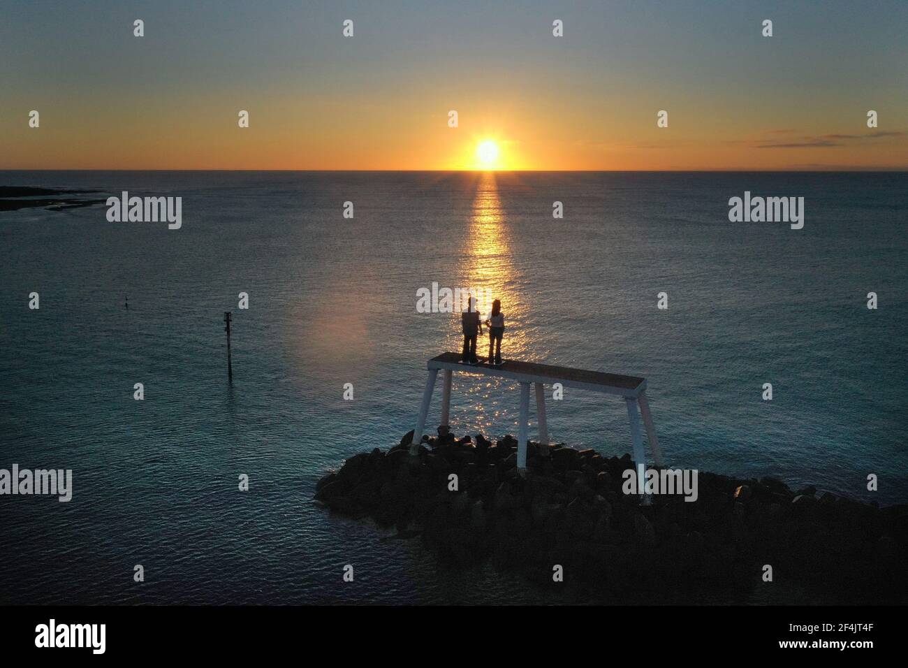 Die Sonne geht über 'The Couple' des Künstlers Sean Henry auf, der vor der Küste bei Newbiggin-by-the-Sea in Northumberland liegt. Bilddatum: Montag, 22. März 2021. Stockfoto