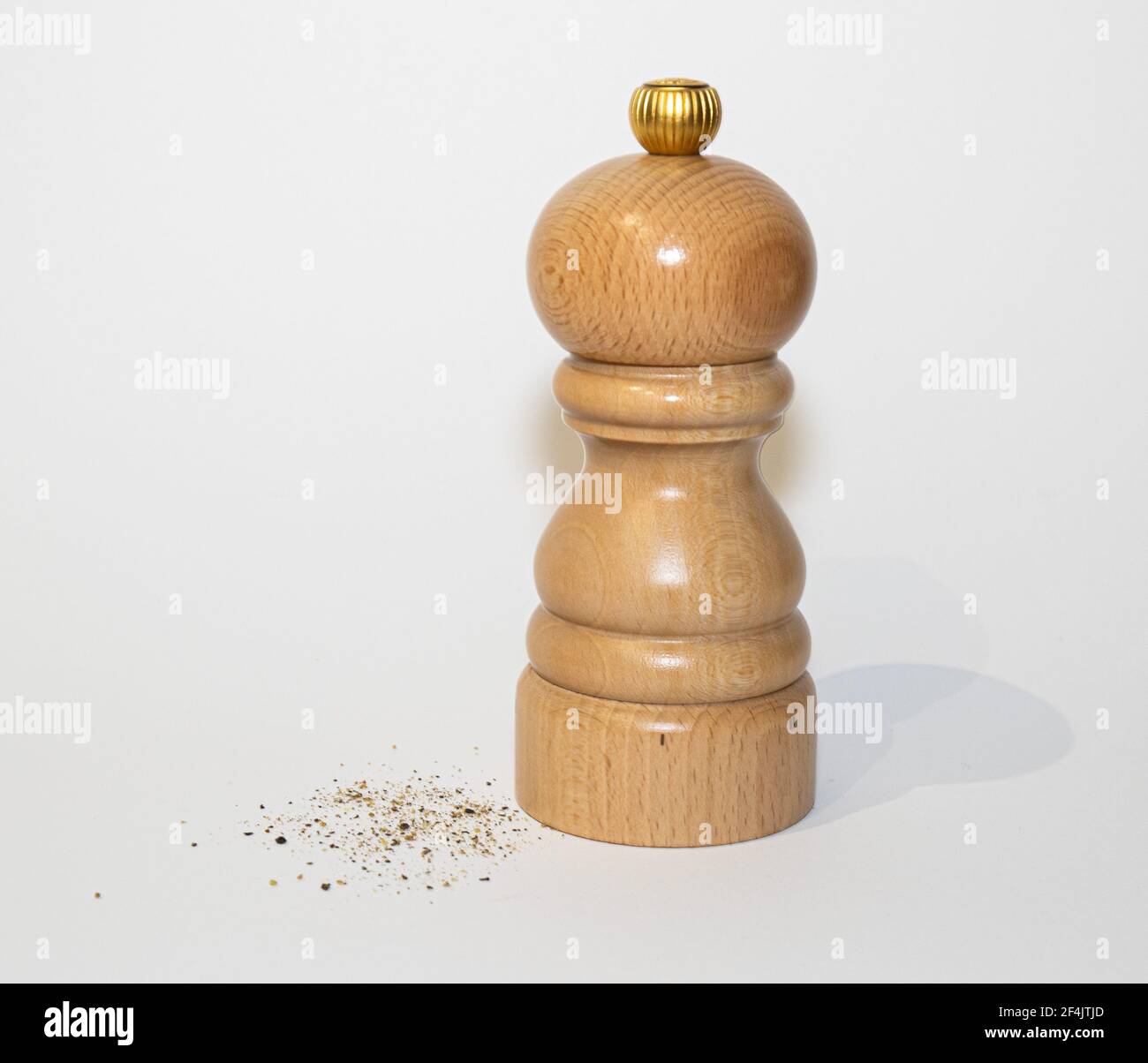Hölzerne Pfeffermühle mit Erdpfeffer daneben Stockfoto