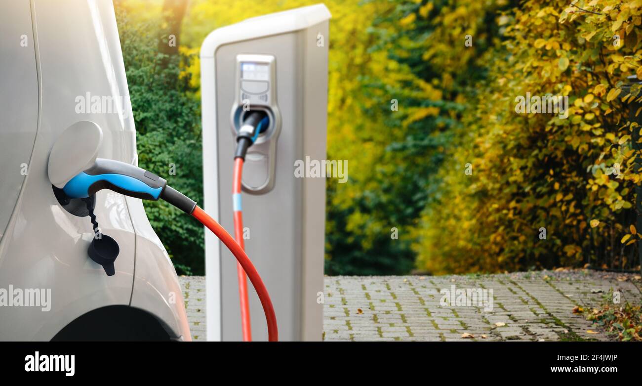 Nahaufnahme eines Elektroautos mit einem angeschlossenen Kabel und Eine Ladestation Stockfoto