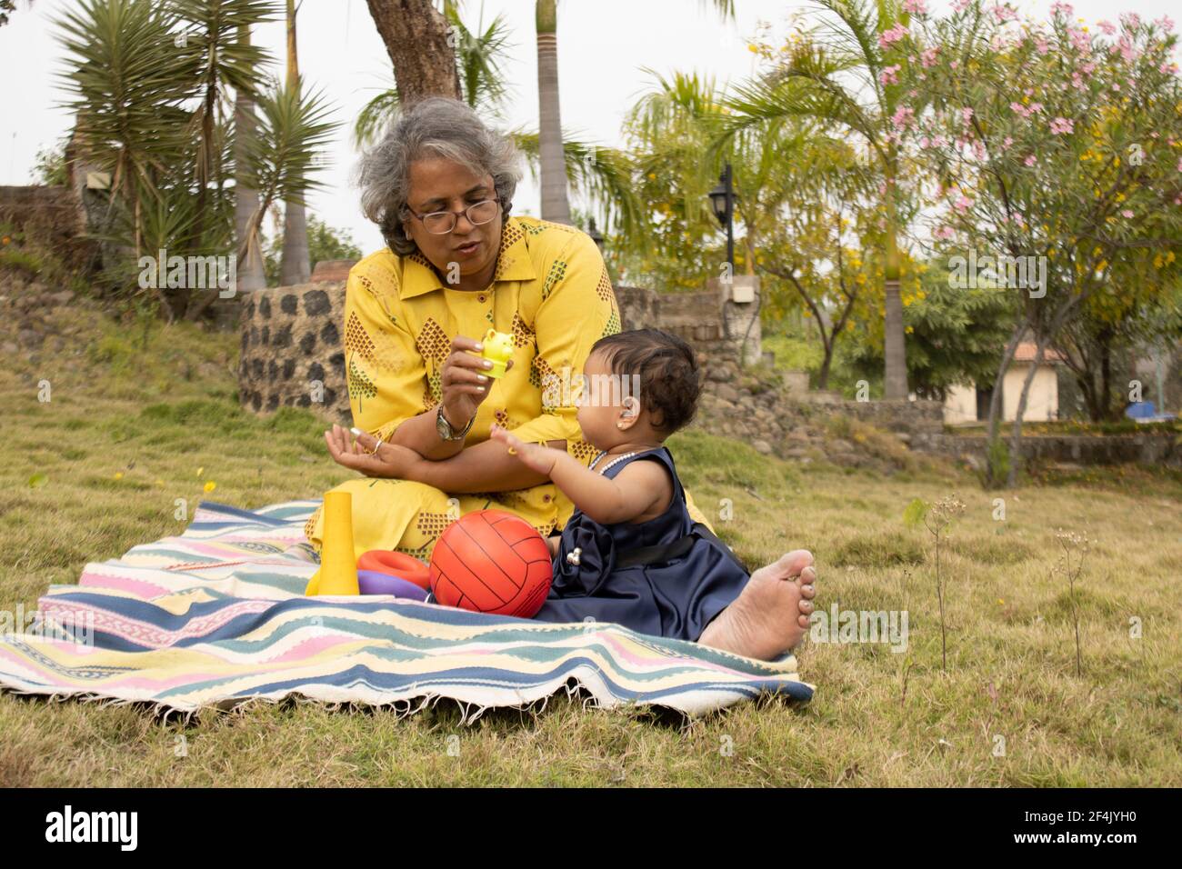 Glückliche Momente mit Oma, indische oder asiatische ältere Dame verbringen Zeit mit ihrer Enkelin im Garten. Stockfoto