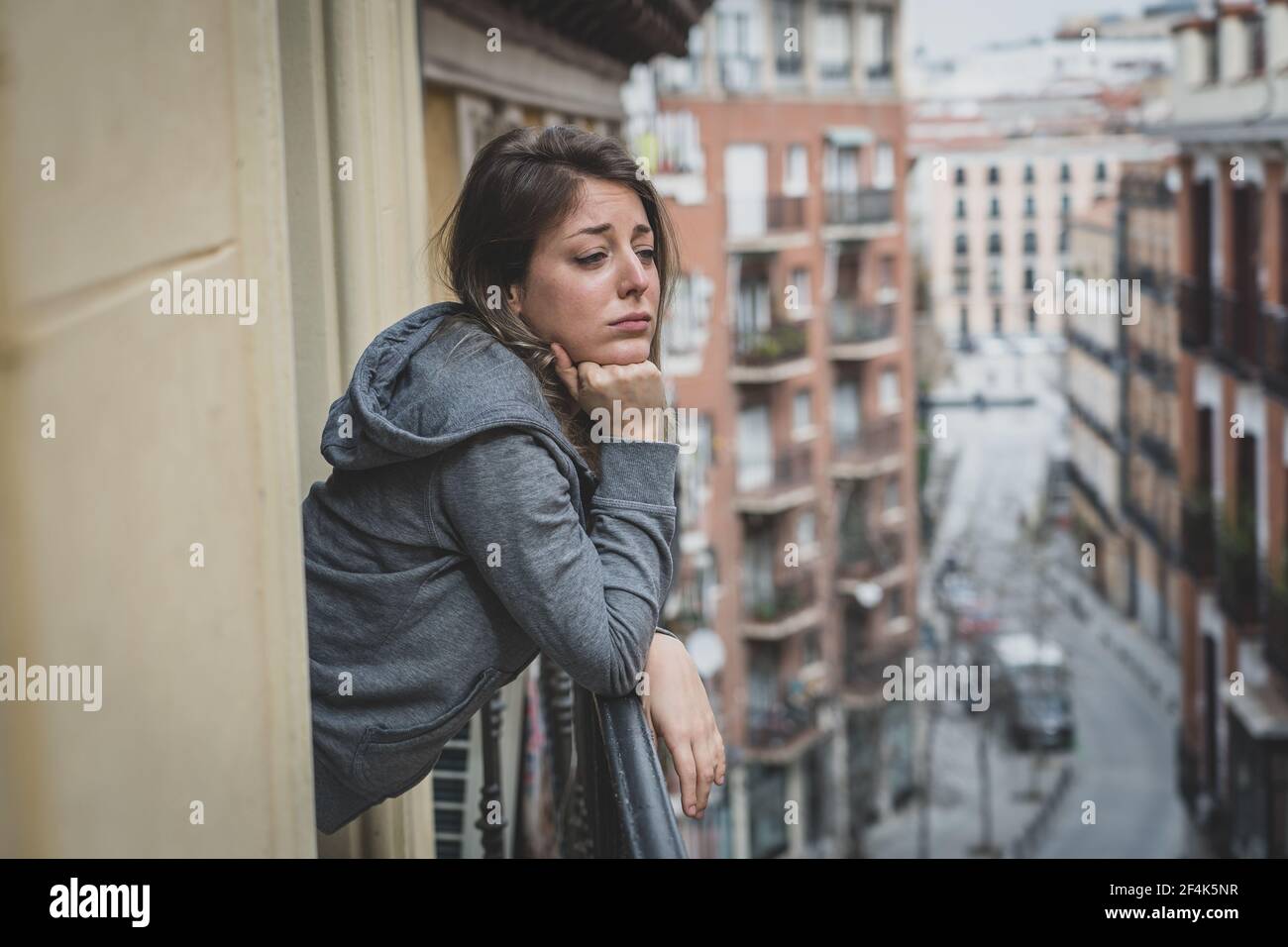 Junge kaukasische traurige und depressive Frau, die auf einem Balkon steht und sich gestresst und überwältigt fühlt. Weiblich leiden an Depressionen in der psychischen Gesundheit conc Stockfoto