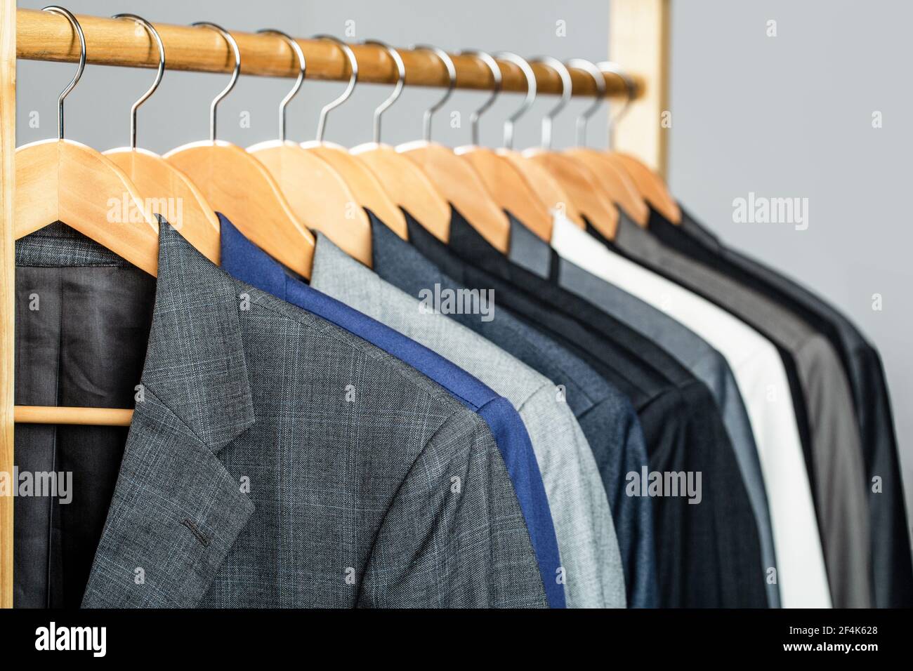 Herrenanzüge in verschiedenen Farben hängen auf Kleiderbügel in einem  Einzelhandelsgeschäft Kleidung, close-up. Herrenhemden, Anzug am Gestell.  Kleiderbügel mit Jacken darauf Stockfotografie - Alamy