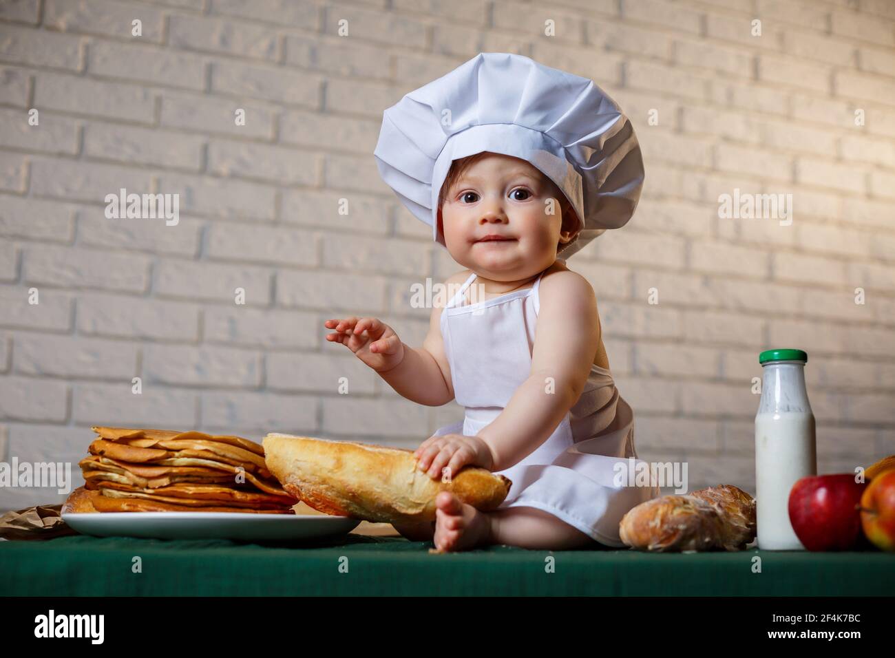 Kleiner Koch. Kleines Kind als Koch gekleidet mit Gebäck, Brötchen, Brot Stockfoto