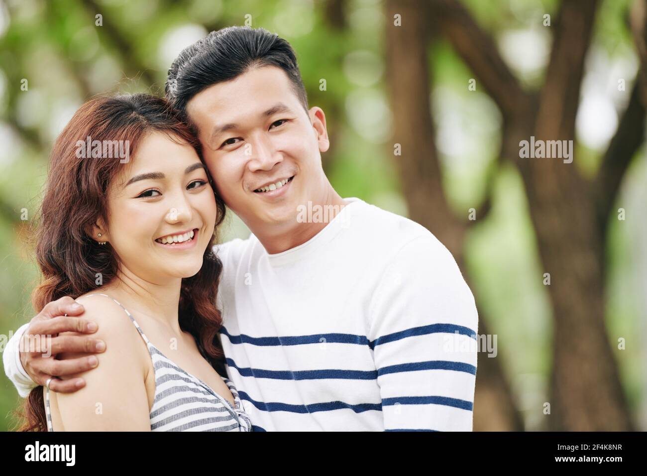 Portrait von glücklich umarmt junge asiatische Freund und Freundin lächelnd Und Blick auf die Kamera Stockfoto