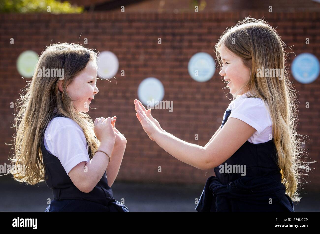Datei Foto vom 08/03/21 von P3 Kindern Scarlett Greggan (links) und Madison Lowry spielen Patty Kuchen während ihrer Mittagspause auf dem Spielplatz der Springfield Primary School in Belfast am ersten Tag zurück für Pre-School, Kindergarten und Grundschule Schüler in P1-P3 in ganz Nordirland. Am Dienstag jährt sich zum ersten Mal die Ankündigung der ersten UK-weiten Sperre am 23. März 2020. Ausgabedatum: Montag, 22. März 2021. Stockfoto