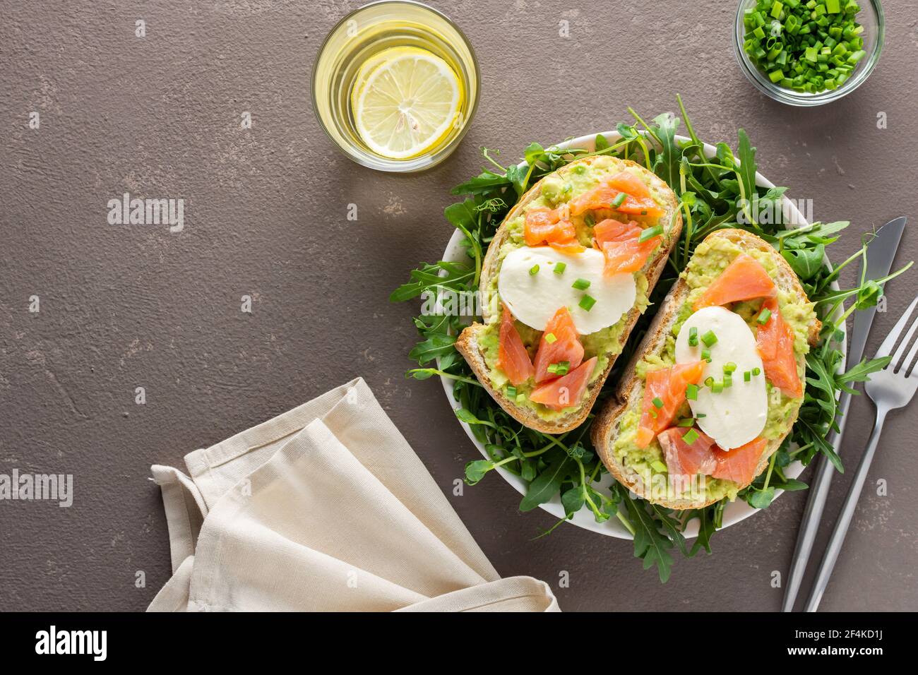 Leckeres herzhaftes Frühstück, Sandwiches mit Avocado-Paste, Lachs und Mozzarella auf einem Teller mit Rucola und Erbsensprossen Stockfoto
