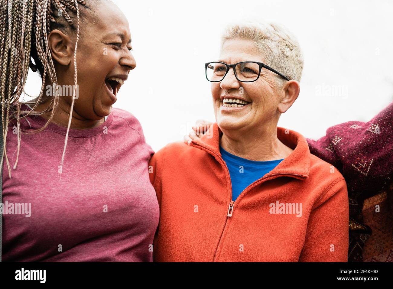 Glückliche ältere Frauen aus verschiedenen Ethnien lachen gemeinsam im Freien - Multirassische reife Freunde mit Spaß - fröhliche ältere Lebensstil - Konzentrieren Sie sich auf Stockfoto