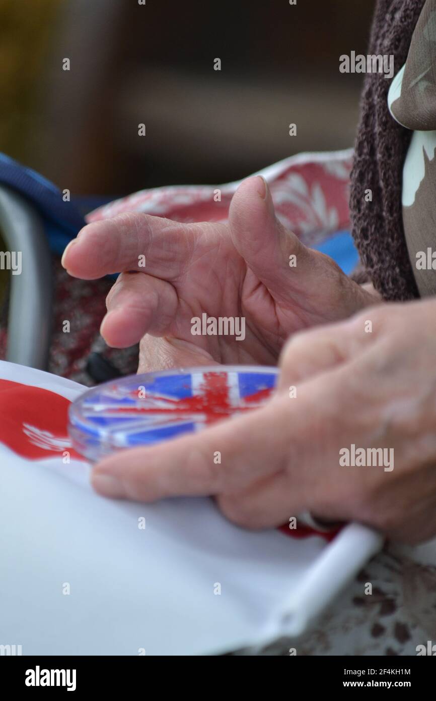 Weibliche Seniorenhände spielen Ein Handheld-Wassergel-Spiel - Fun Times - Union Jack Game - Finger - bewegliche Hände und Finger - Großbritannien Stockfoto