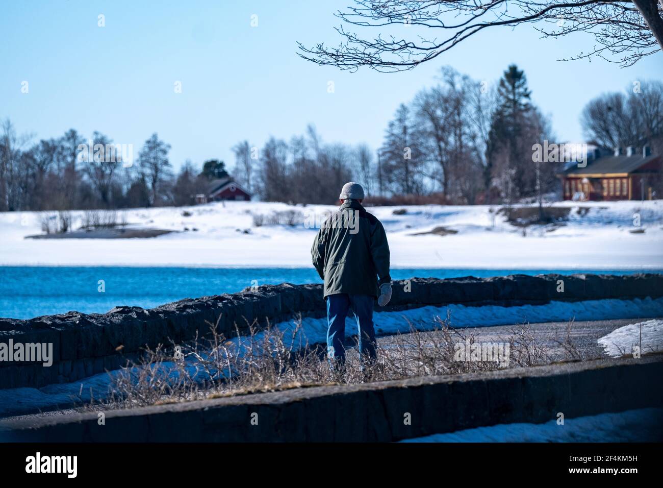 Helsinki / Finnland - 22. MÄRZ 2021: Ein alleinstehender Mann, der an einem sonnigen Frühlingsmorgen auf dem Strandboulevard läuft. Stockfoto