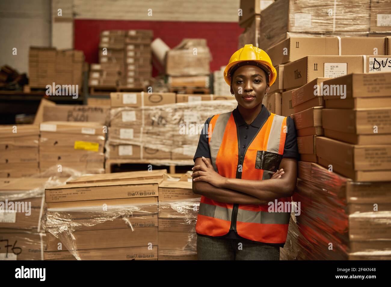 Afrikanische Lagerarbeiterin, die neben einigen Kisten steht Stockfoto