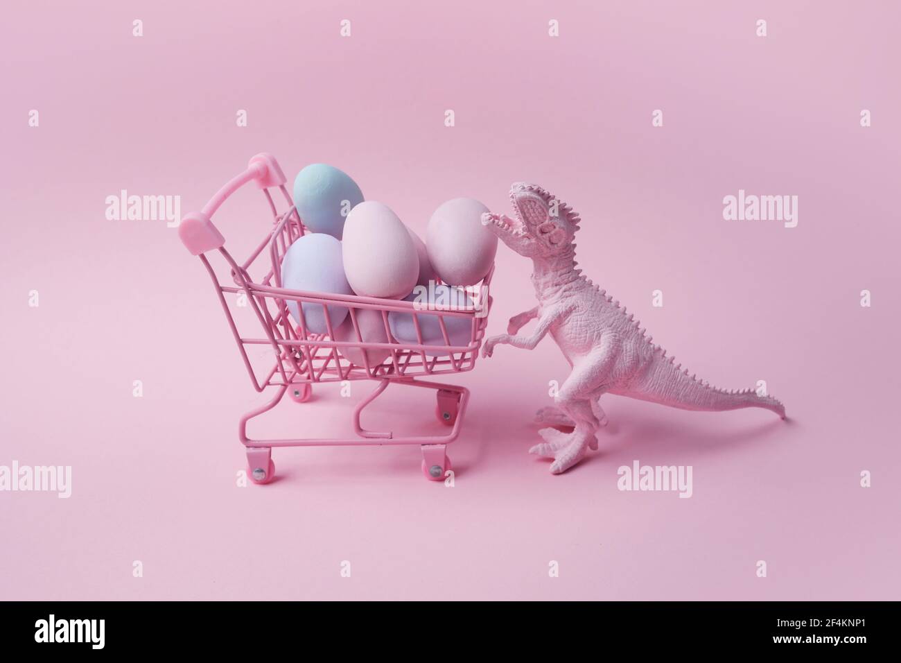 T rex Dinosaurier mit Einkaufswagen und Eiern auf rosa Hintergrund. Ostern Mega Sale Konzept. Stockfoto