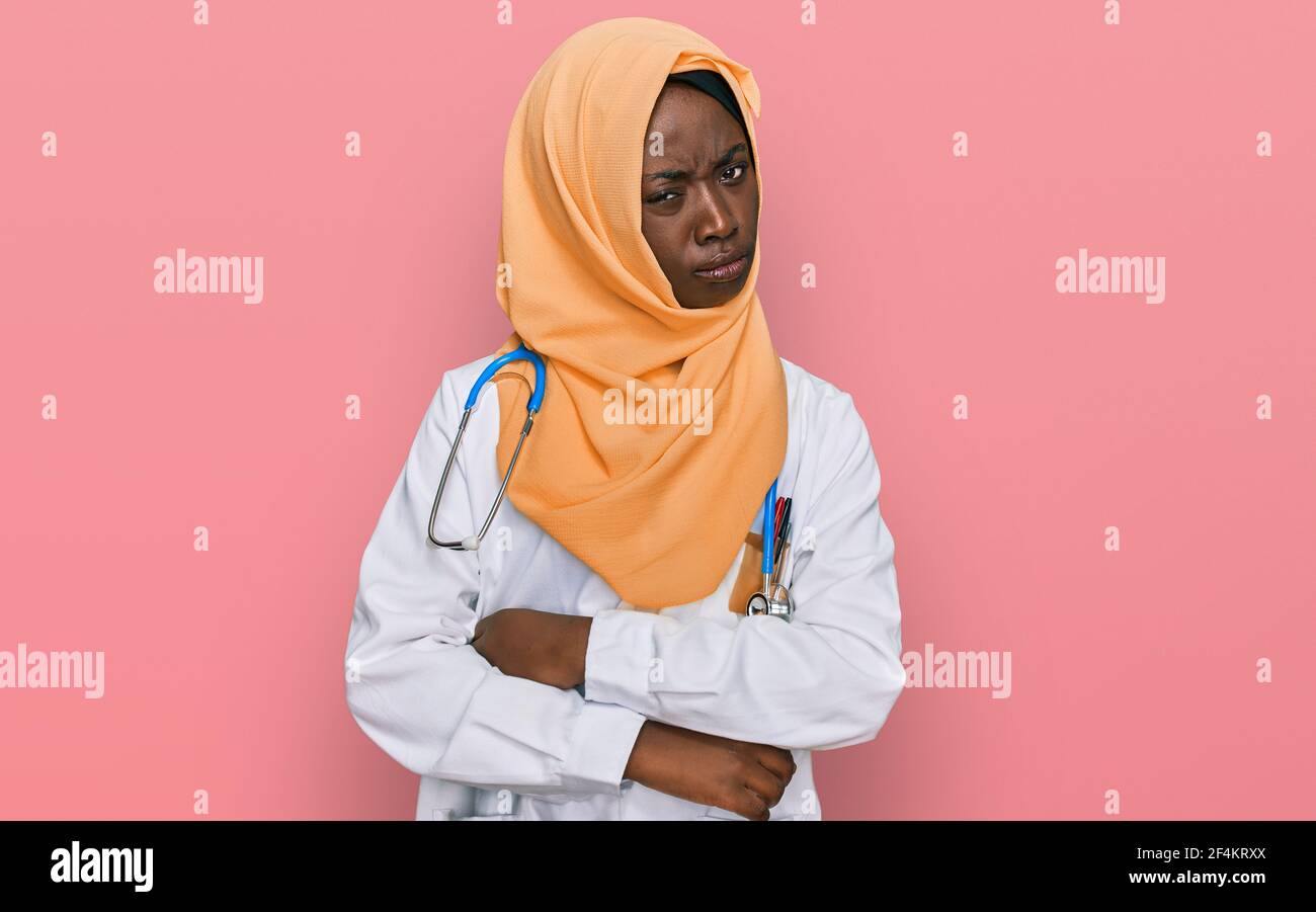 Schöne afrikanische junge Frau trägt Arzt Uniform und Hijab Skeptiker und nervös, missbilligend Ausdruck auf Gesicht mit gekreuzten Armen. Negative Person Stockfoto
