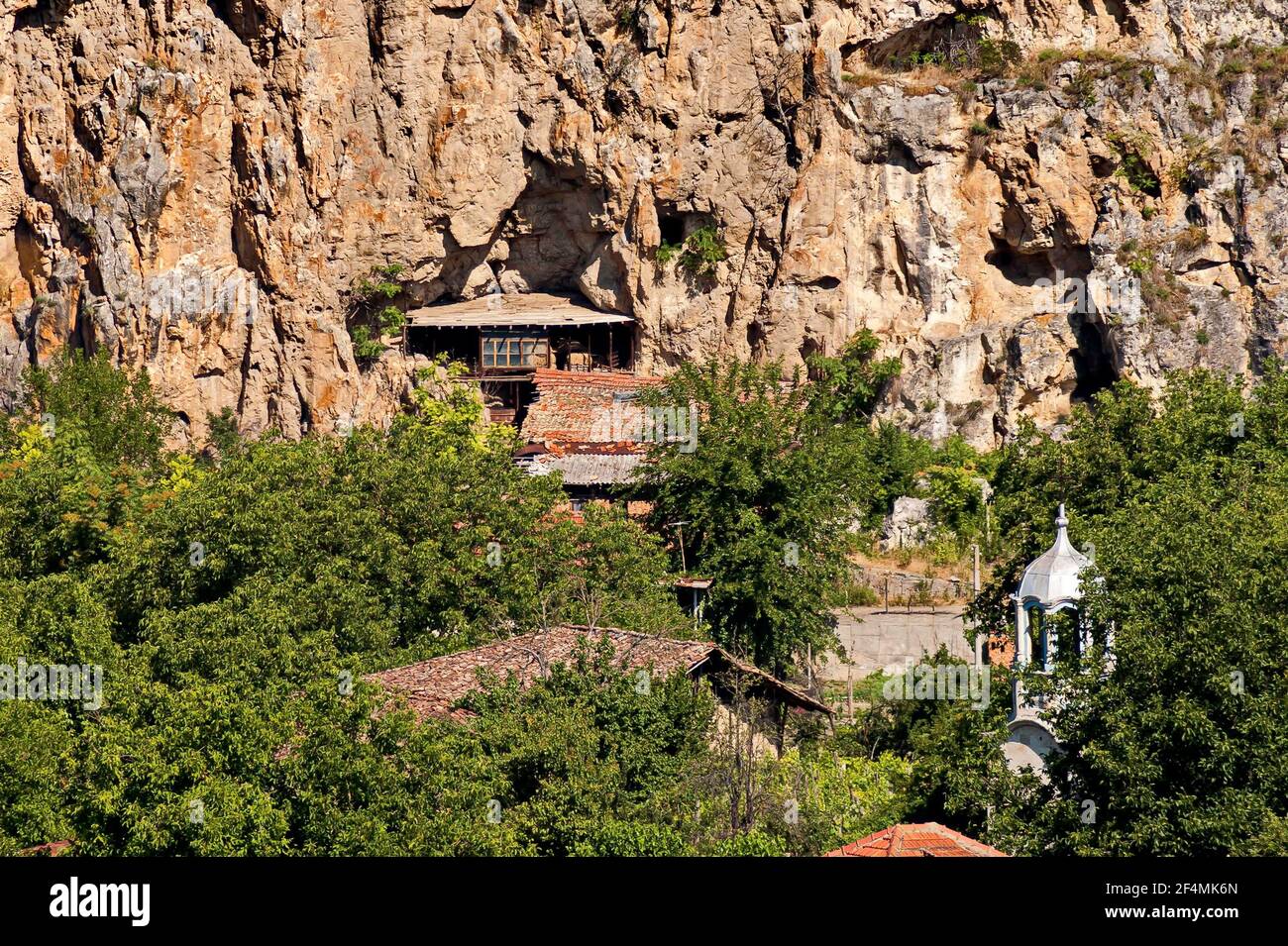 Blick auf das schöne Dorf Nisovo, Bulgarien, unter, über und in den hohen Kalkfelsen, durch herrliche Laubbäume geschützt Stockfoto