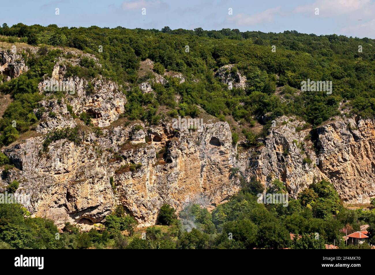 Blick auf das schöne Dorf Nisovo, Bulgarien, unter, über und in den hohen Kalkfelsen, durch herrliche Laubbäume geschützt Stockfoto