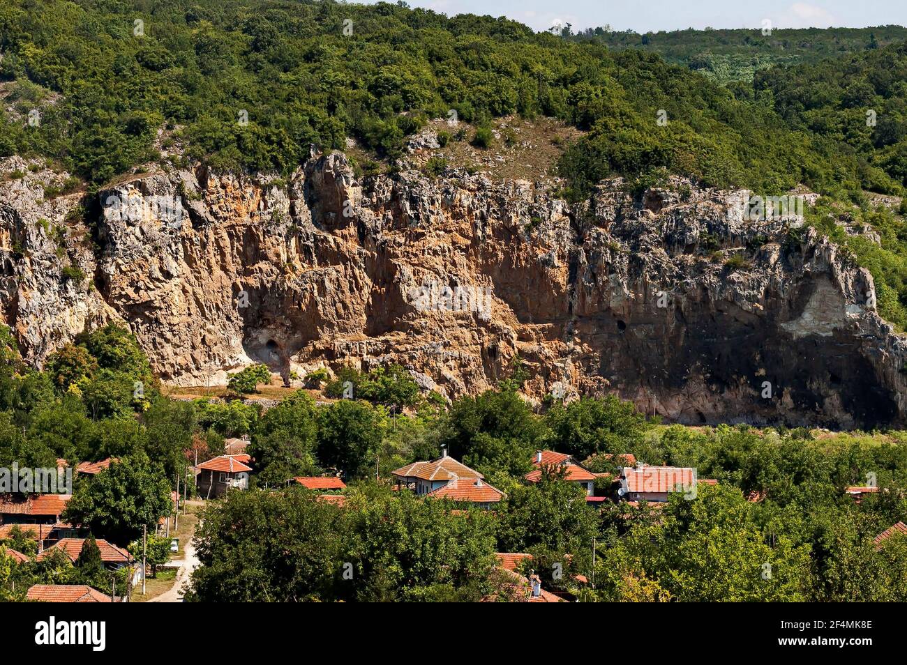 Blick auf das schöne Dorf Nisovo, Bulgarien, unter, über und in den hohen Kalkfelsen, durch herrliche Laubbäume geschützt Stockfoto