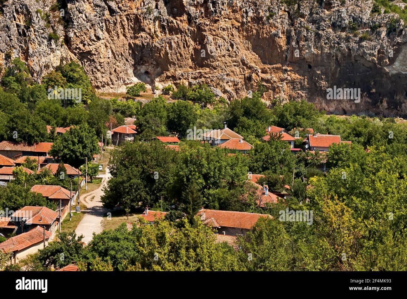 Blick auf das schöne Dorf Nisovo, Bulgarien, unter, über und in den hohen Kalkfelsen, durch herrliche Laubbäume geschützt Stockfoto
