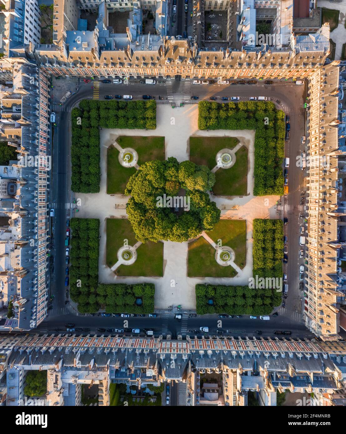 Top Down Luftaufnahme des grünen Parkplatzes am Place des Vosges, umgeben von Dächern traditioneller Gebäude in Paris, Frankreich Stockfoto