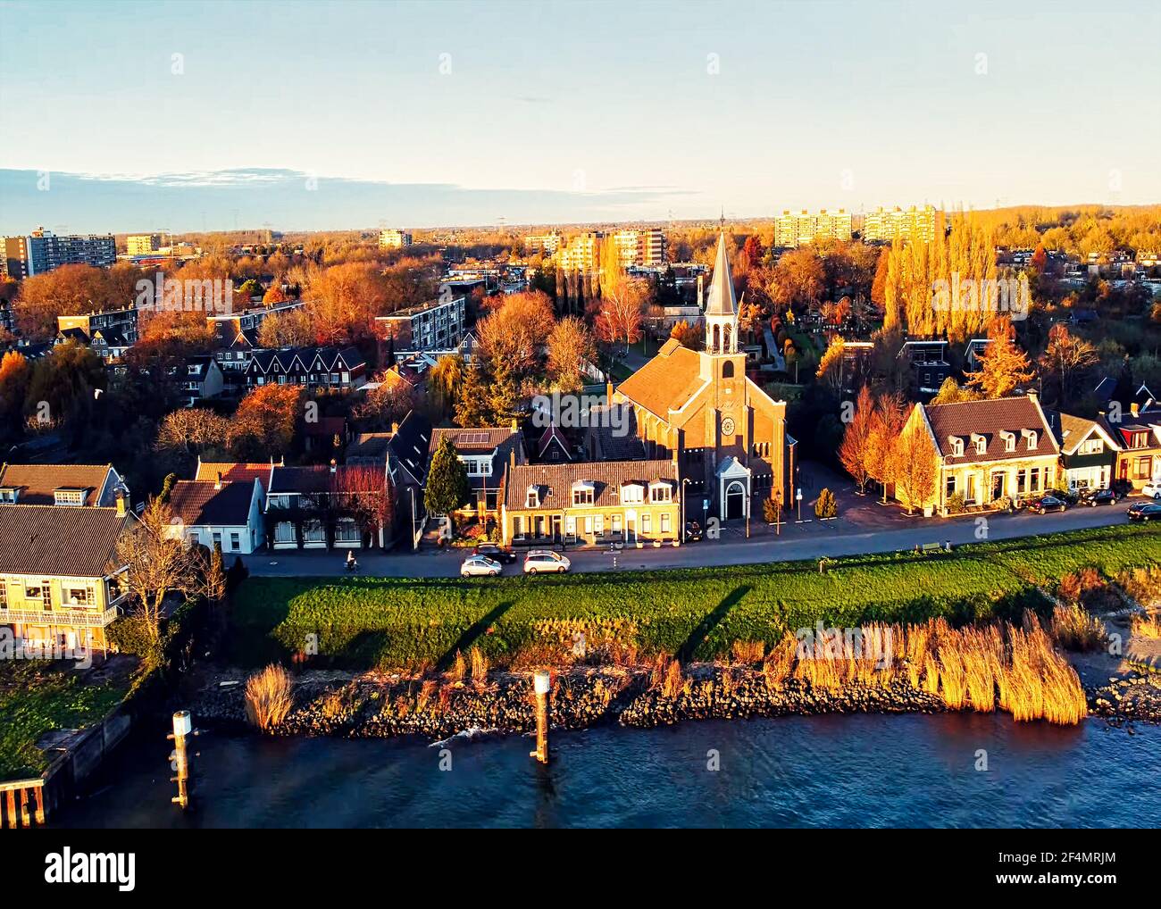 Dies ist ein Drohnenbild. Es ist entlang des niederländischen Flusses Merwede aufgenommen. Es zeigt einen Teil des Dorfes Papendrecht. Die Hauptkirche ist sichtbar. Stockfoto