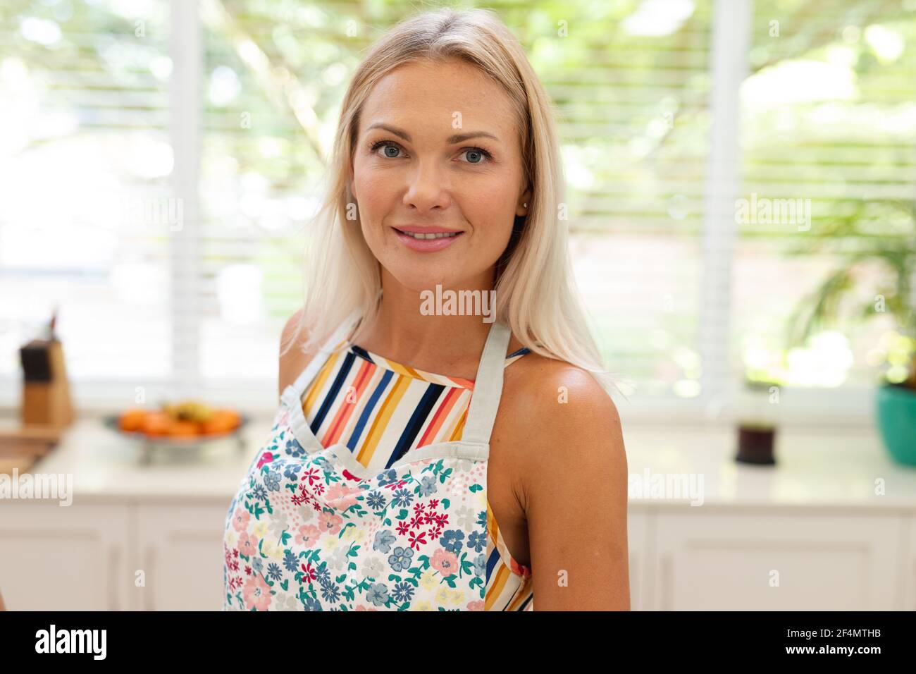 Porträt einer lächelnden kaukasischen Frau mit Schürze in der Küche Stockfoto