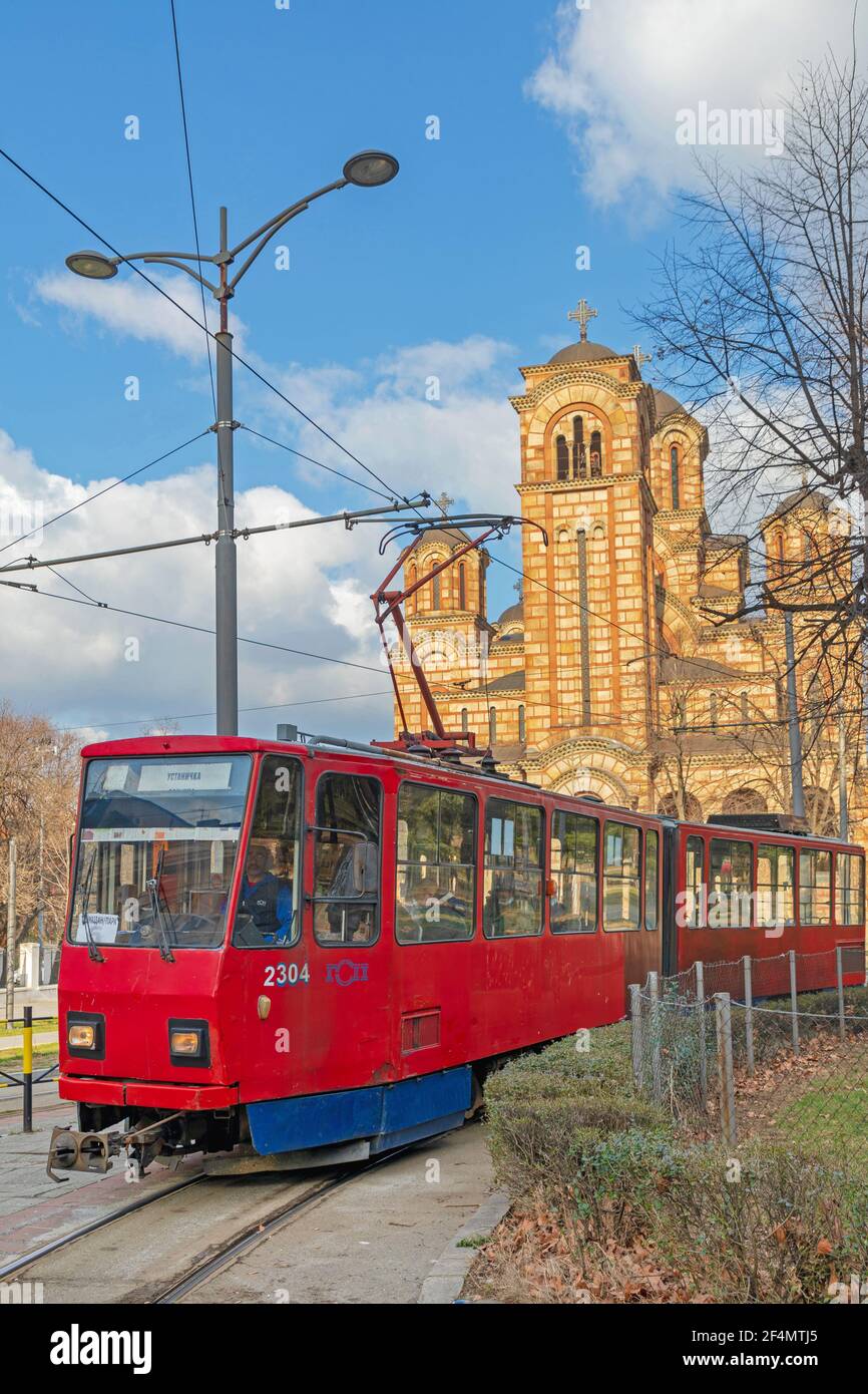 Belgrad, Serbien - 14. Februar 2021: Rote Straßenbahn vor der St. Marks Orthodoxen Kirche am Wintertag Tasmajdan Stockfoto