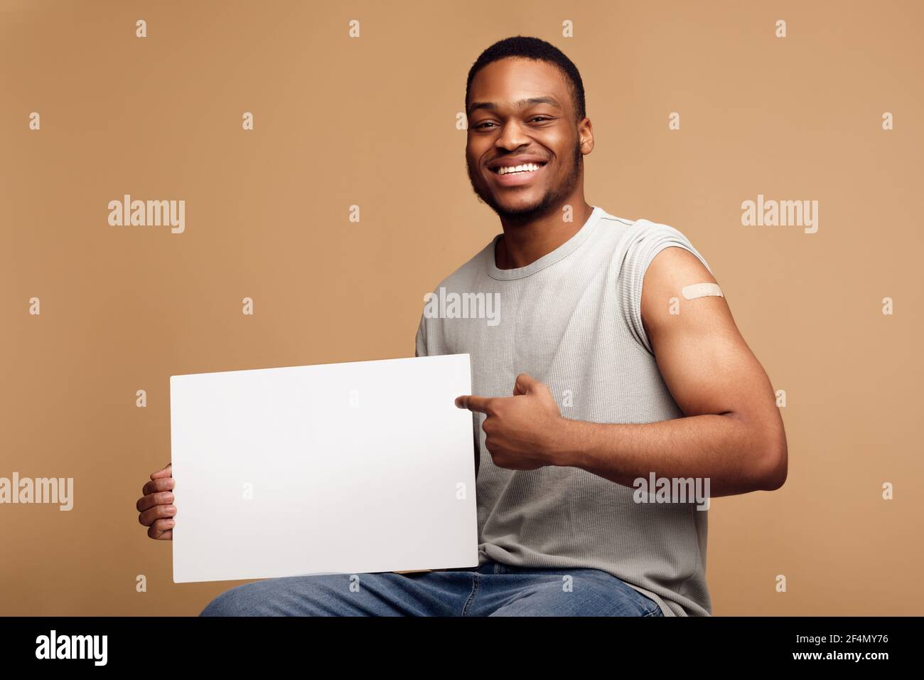 Geimpfter Schwarzer Mann Hält Leere Poster Werbung Impfung, Beige Hintergrund Stockfoto