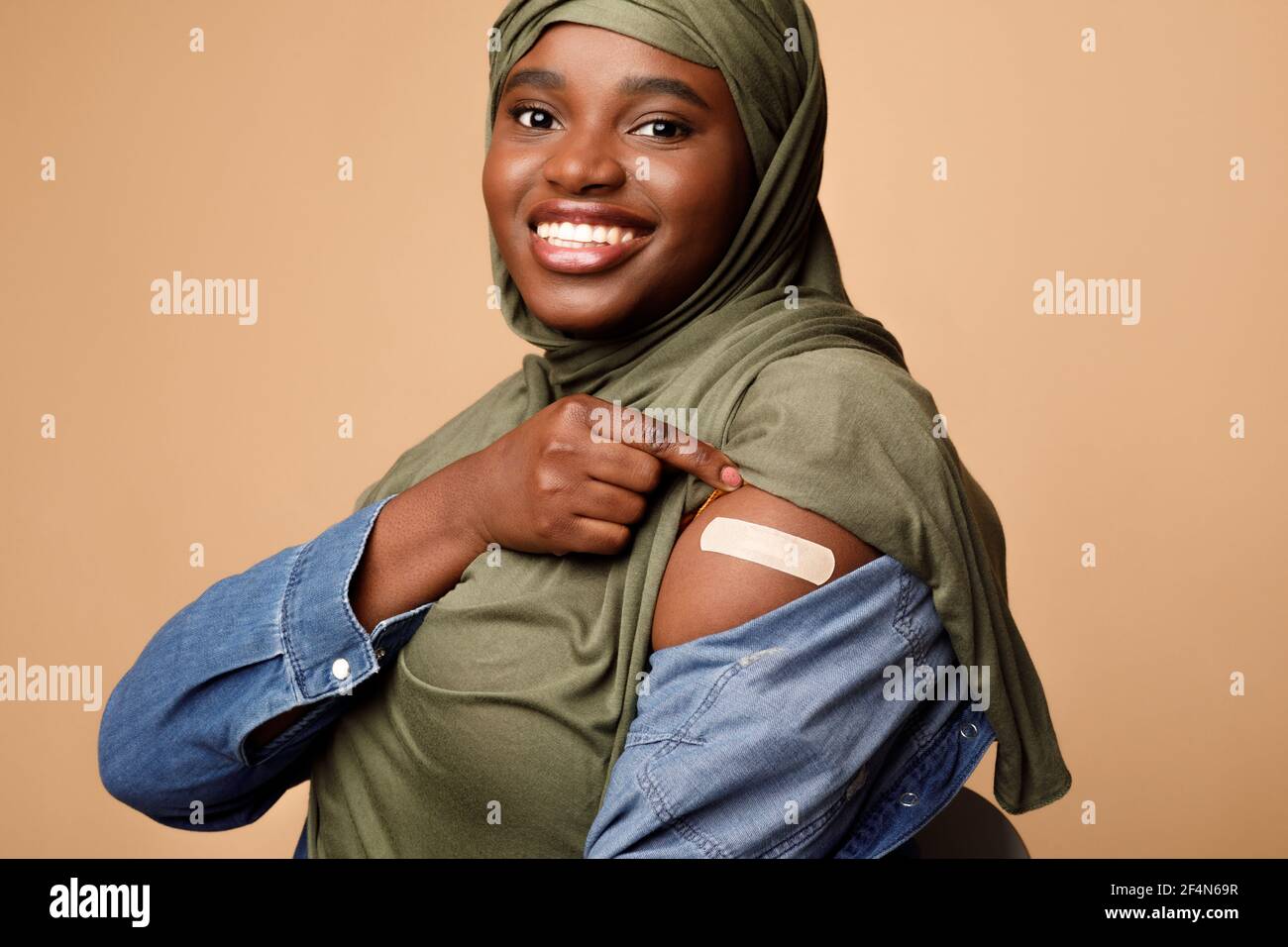 Muslim Lady Zeigt Geimpften Arm Nach Impfung Injektion, Beige Hintergrund Stockfoto