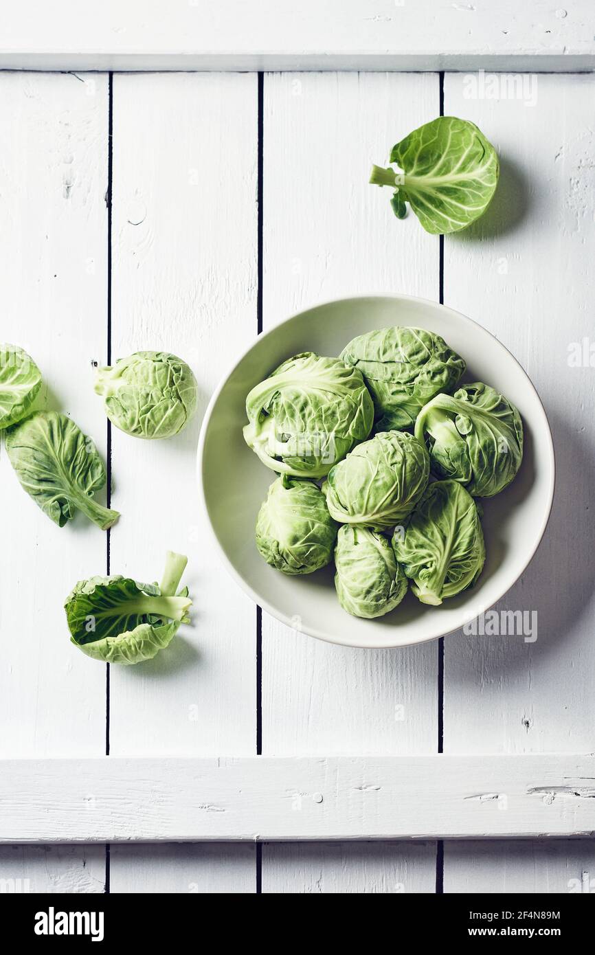 Frische rohe rosenkohl in einer Schüssel auf einem weißen Holztisch, Draufsicht. Stockfoto