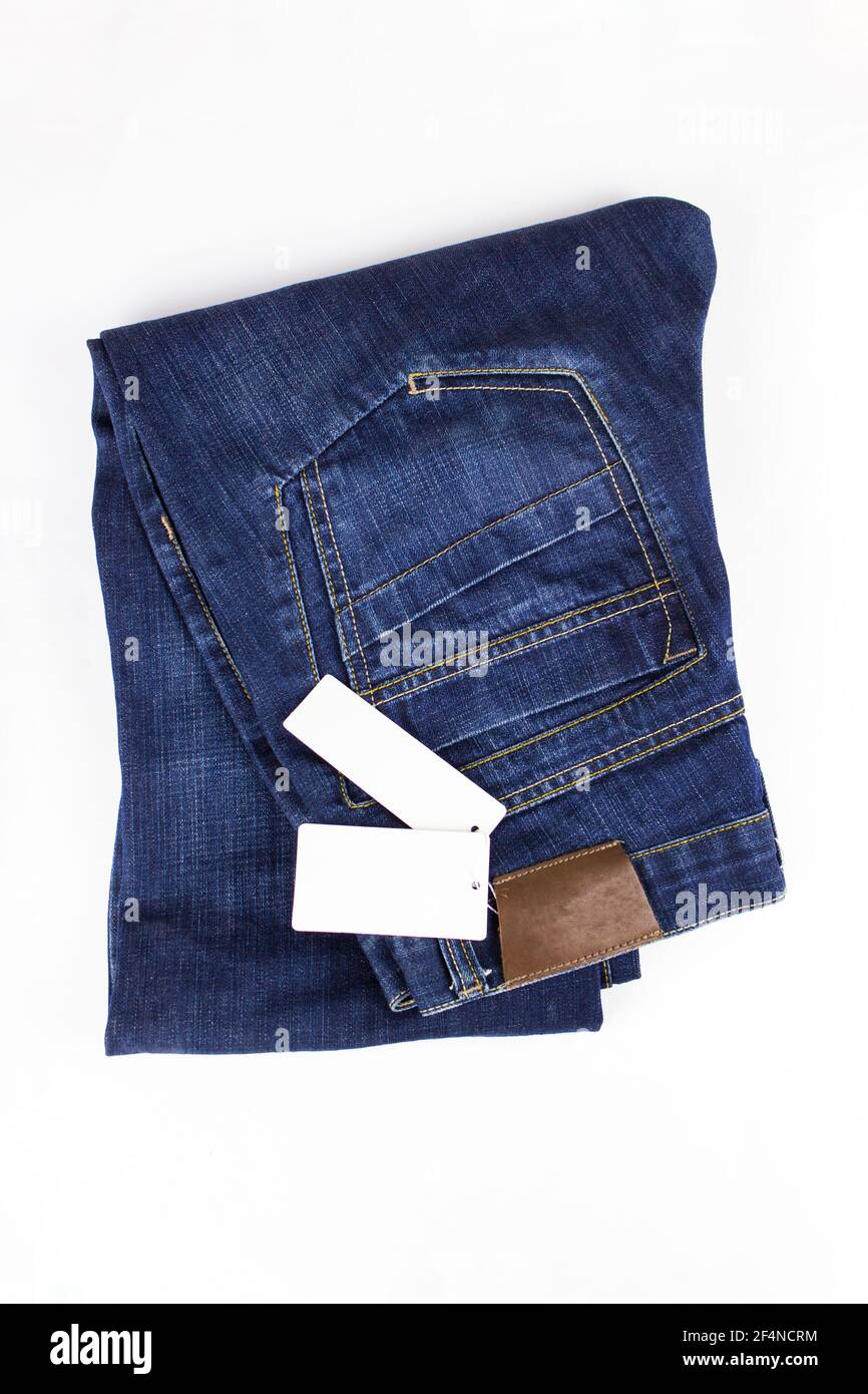 Modischer Jeans-Knopf. Blaue Jeans auf weißem Hintergrund mit Preisschild. Speicherplatz kopieren. Kleidung, Online-Shop Konzepte Stockfoto