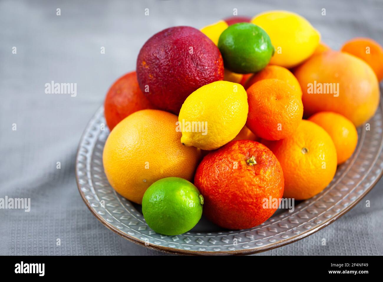 Frische saftige Zitrusfrüchte - Orangen, Mandarinen, Zitronen und Limetten, auf grauem Hintergrund Stockfoto
