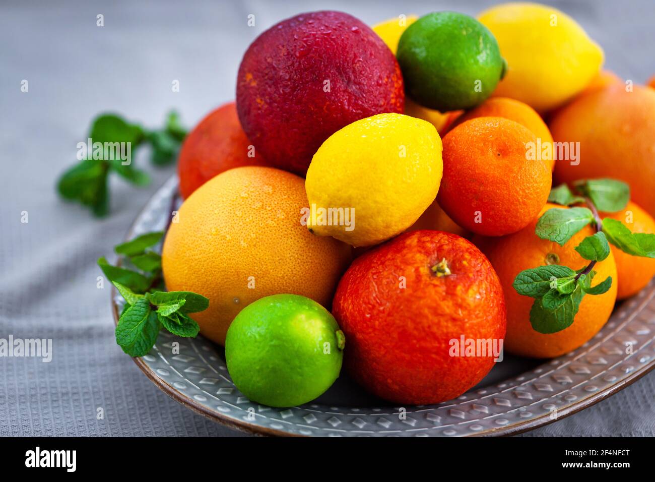 Frische saftige Zitrusfrüchte - Orangen, Mandarinen, Zitronen und Limetten, auf grauem Hintergrund Stockfoto