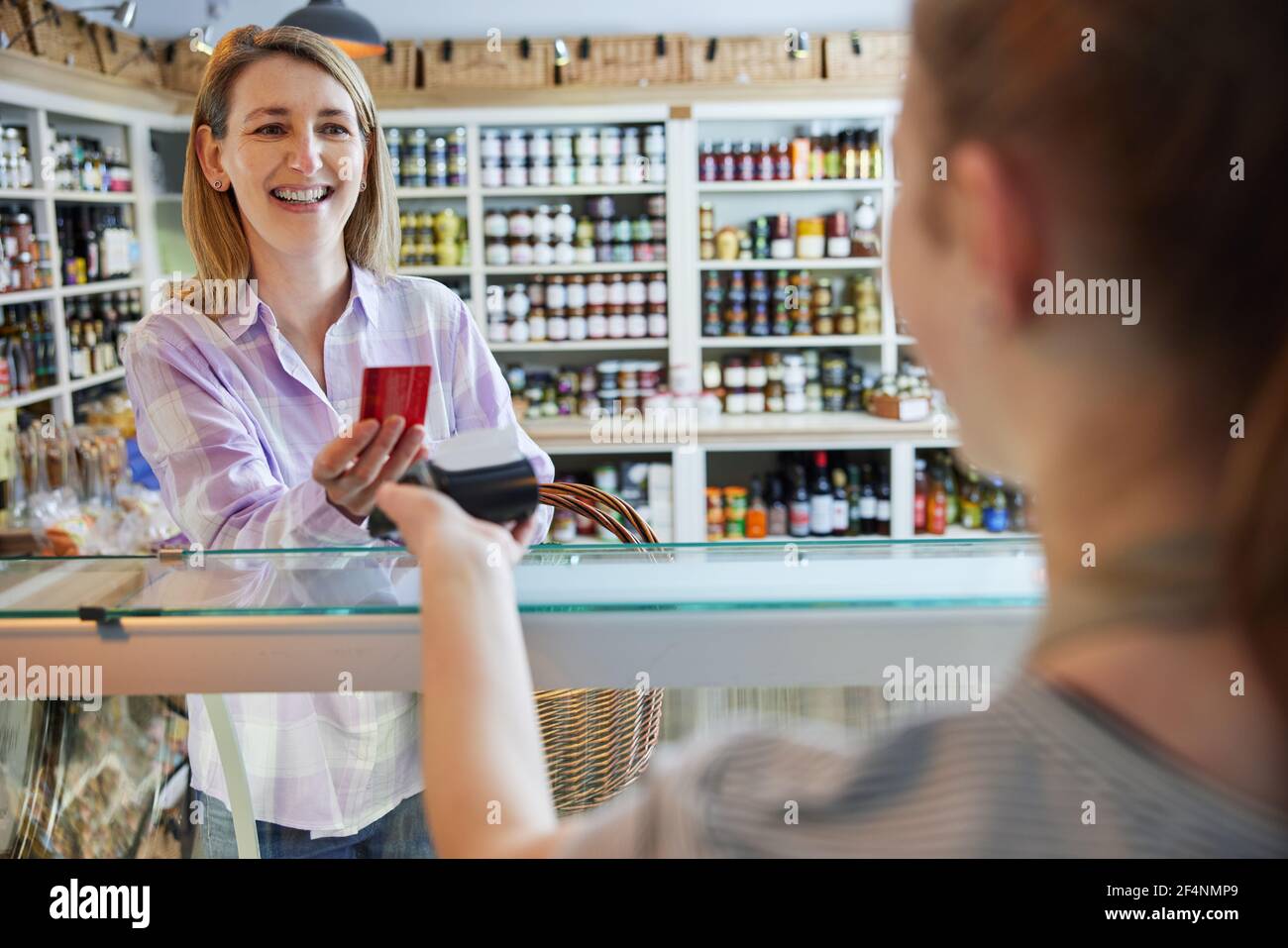 Lächelnd Weiblich Kunde Feinkostgeschäft Herstellung Kontaktlose Zahlung Mit Karte Für Shopping An Sales Assistant Stockfoto