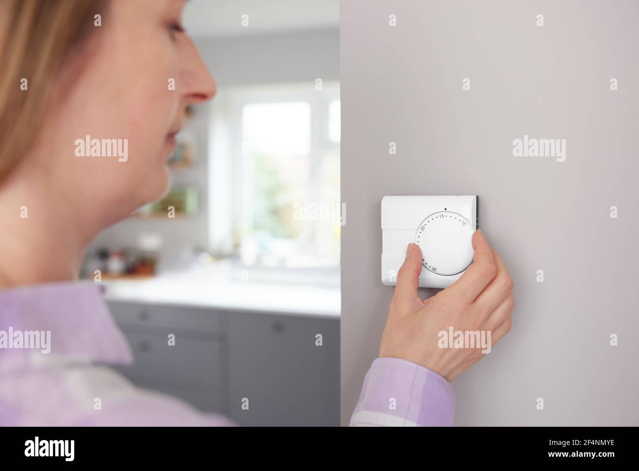 Frau Zu Hause In Der Küche Drehen Nach Unten Zentralheizung Thermostat Um Energie und Geld zu sparen Stockfoto