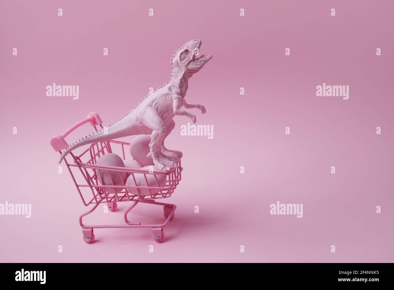 T rex Dinosaurier mit Einkaufswagen und Eiern auf rosa Hintergrund. Ostern Mega Sale Konzept. Stockfoto