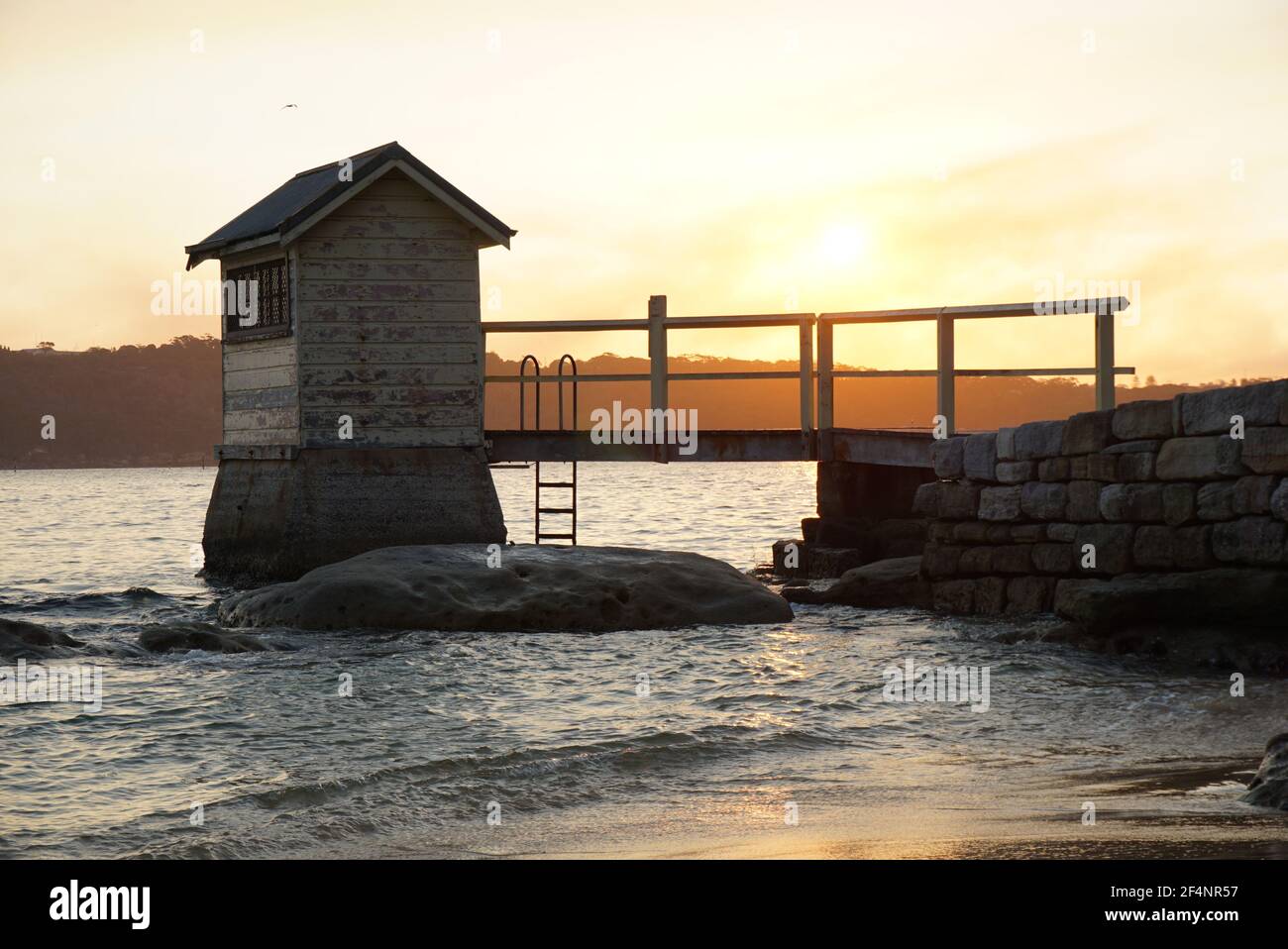 Watsons Bay, Sydney, NSW Australien - Sonnenuntergang hinter einer kleinen Hütte und Brücke in Camp Cove Beach Stockfoto