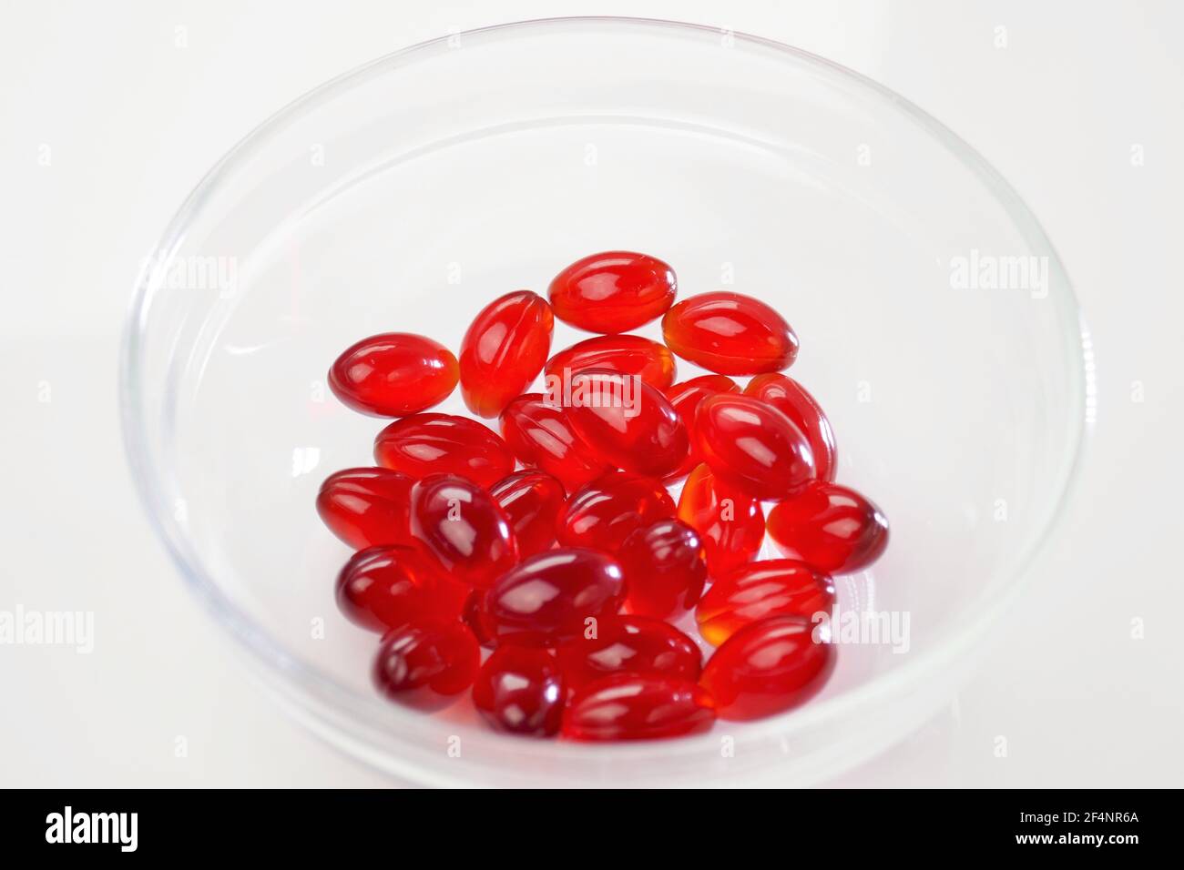 Krillöl. Rote Gelatine Kapseln mit Krillöl in einer transparenten Glas Tasse auf weißem Hintergrund.Quelle von Omega-Fettsäuren.Nahrungsergänzungsmittel Stockfoto