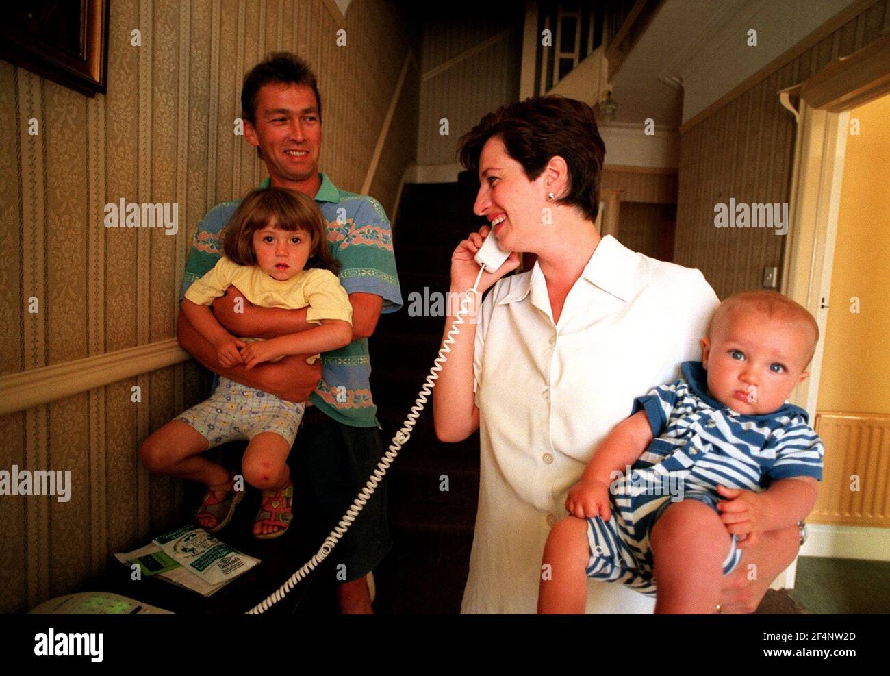 Ruth und Hugh Deans mit ihren Kindern Juli 1999Alice 3 und Baby Harry stehen im Flur ihres Hauses am Telefon sprechen. Workaholic Feature Story Stockfoto