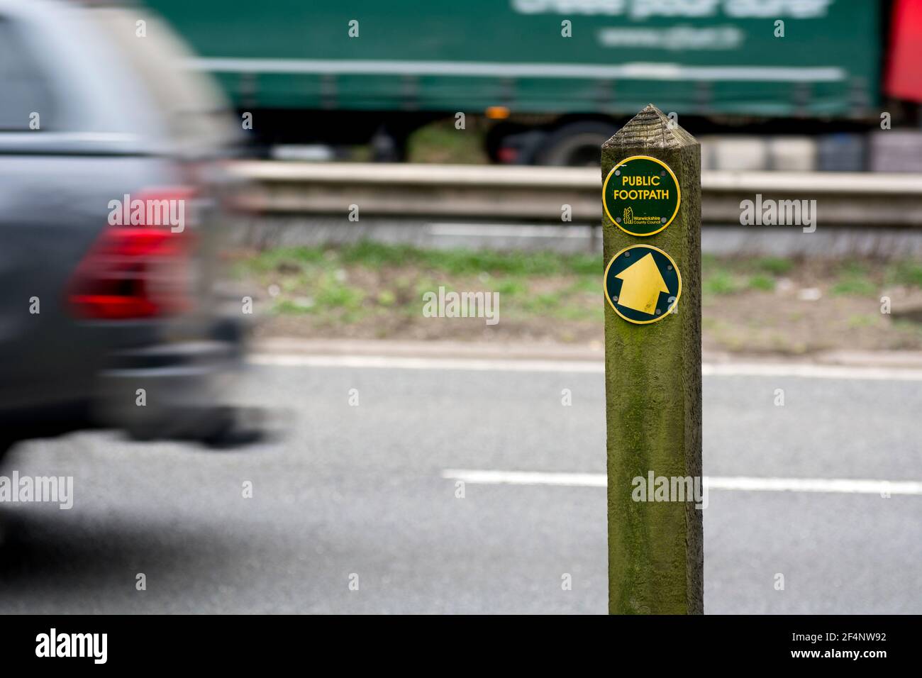 Öffentliches Wanderwegschild, wo der Weg die Straße A46 kreuzt, Hampton Magna, Warwickshire, Großbritannien Stockfoto