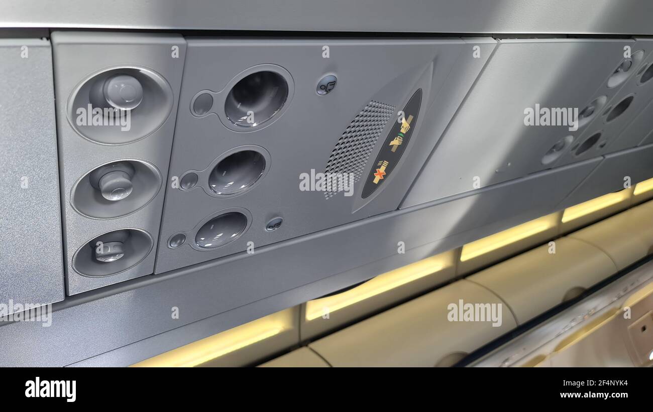 Sicherheitsgurt, Rauchverbotsschild, Licht und Luftströmungsdüse an einem Passagierflugzeug befestigen Stockfoto