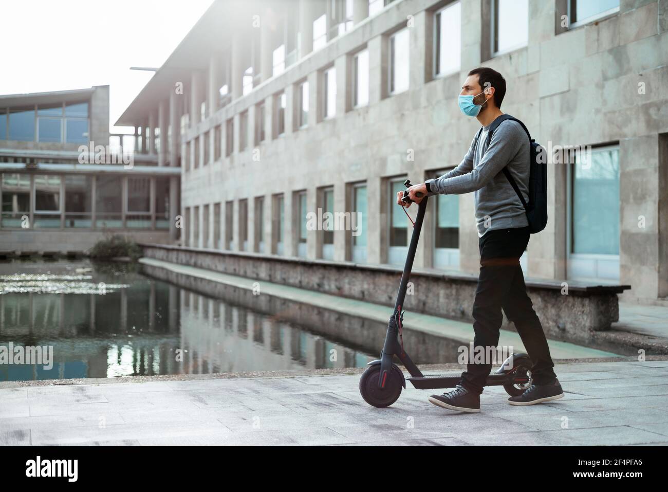 Stilvoller Mann zu Fuß in der Nähe Elektroroller auf der Straße Stockfoto