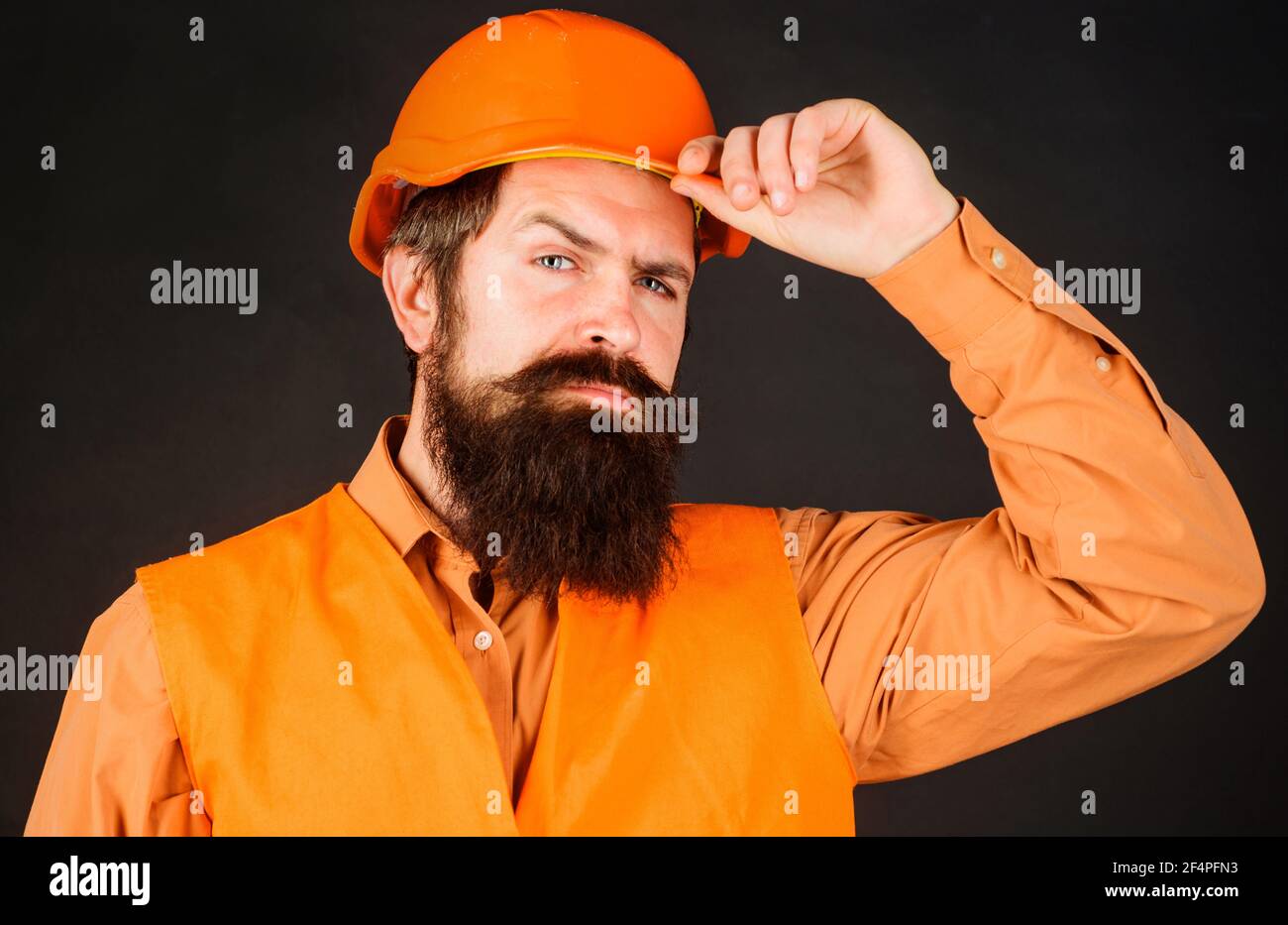 Professioneller Schwerindustrie-Ingenieur. Bauarbeiter in Hut. Bärtiger Mann in Sicherheitsuniform und Helm. Männlicher Baumeister. Stockfoto