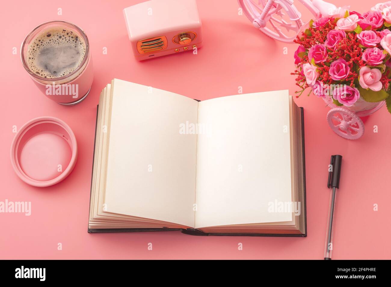 Kreativität inspirierendes Arbeitsplatzkonzept mit Blick von oben auf einen Schreibtisch, Vintage-Radio, heiße Tasse Kaffee und einen Stift neben einem offenen Buch oder Journal isoliert auf Stockfoto