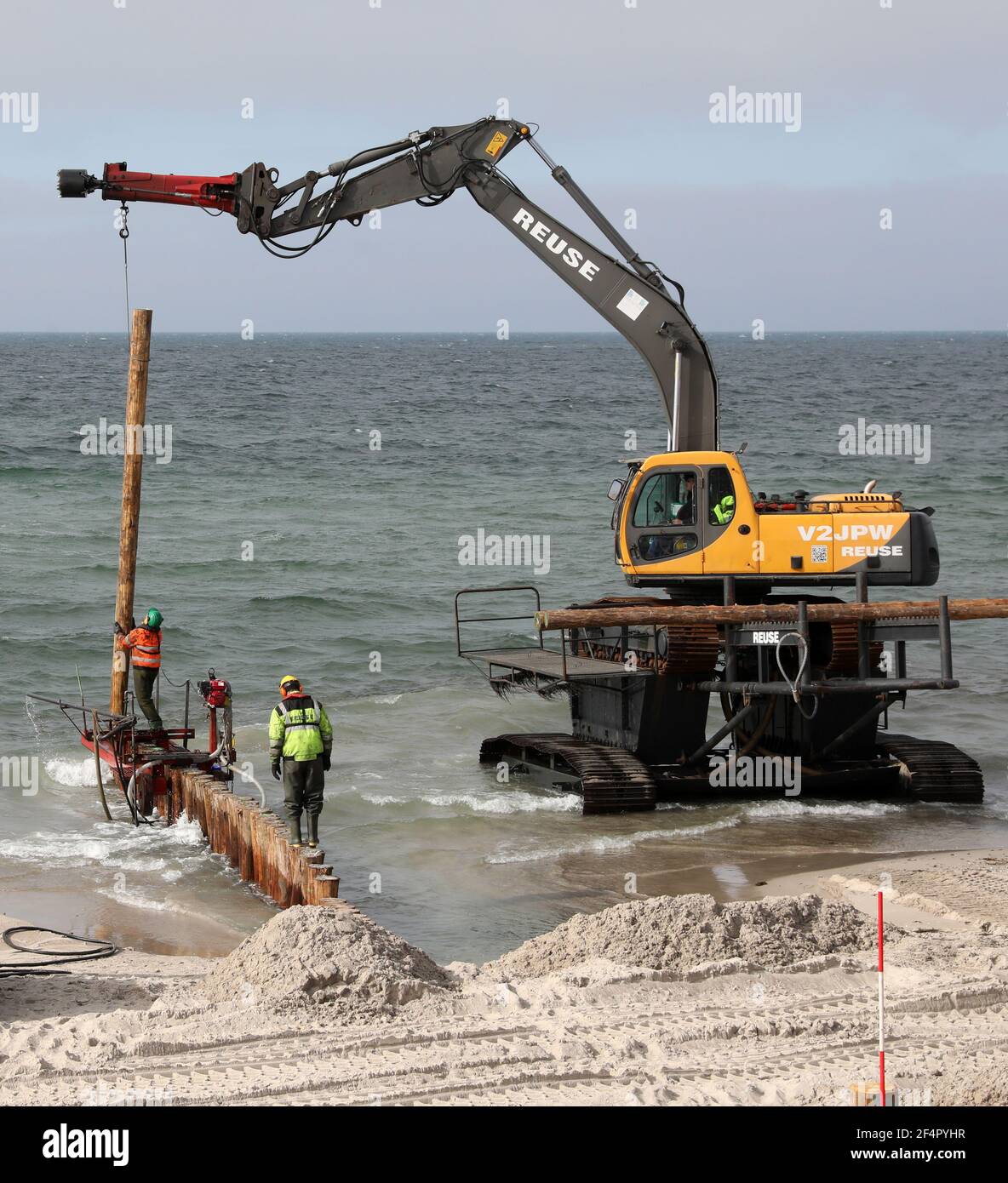 Ahrenshoop, Deutschland. März 2021, 22nd. Im Ostseebad auf der Halbinsel Fischland-Darß-Zingst, die von der Schiffsbohrung beschädigt wurden, werden mit Schwertechnologie Groynes wieder aufgebaut. Von November 2020 bis April 2021 werden insgesamt 4.600 Pfähle neu gefahren, der neue Groyne-Ersatz wird zwei Millionen Euro kosten. Am Strand wird Kiefernholz verwendet, während im Wasser Eukalyptus aus Plantagenanbau verwendet wird, der der Borer des Schiffes standhalten kann. Quelle: Bernd Wüstneck/dpa-Zentralbild/ZB/dpa/Alamy Live News Stockfoto