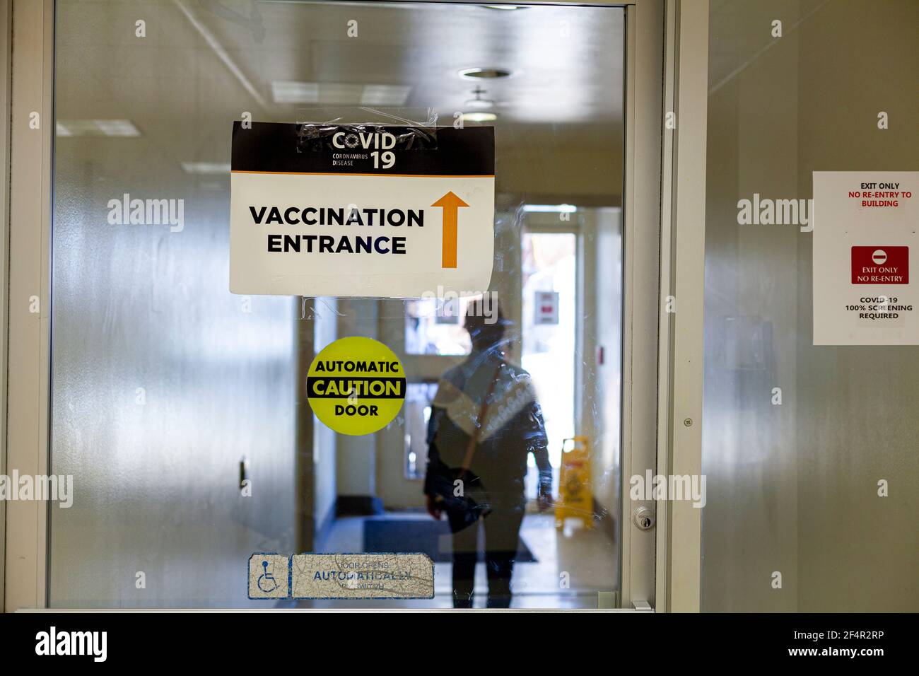 Bild zeigt das Innere einer Gesundheitseinrichtung mit Glas Automatische Tür mit einem Schild auf der Aufschrift Eingang von Die Impfstelle COVID-19 Stockfoto