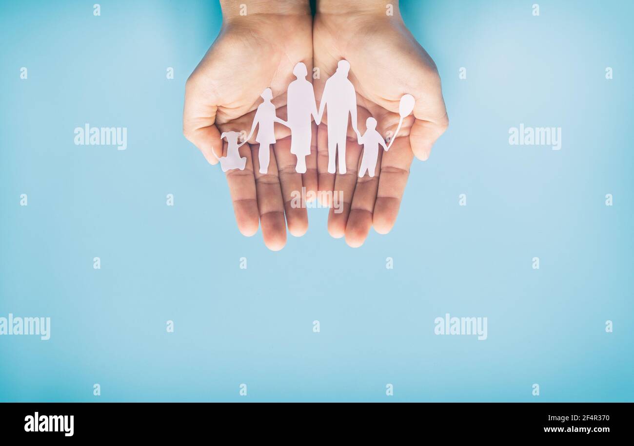 Hand halten Familie Papier auf blauem Hintergrund geschnitten. Familientag Konzept, Pflege, häusliche Gewalt, Homeschool, internationaler Tag der Familien, Welt Stockfoto