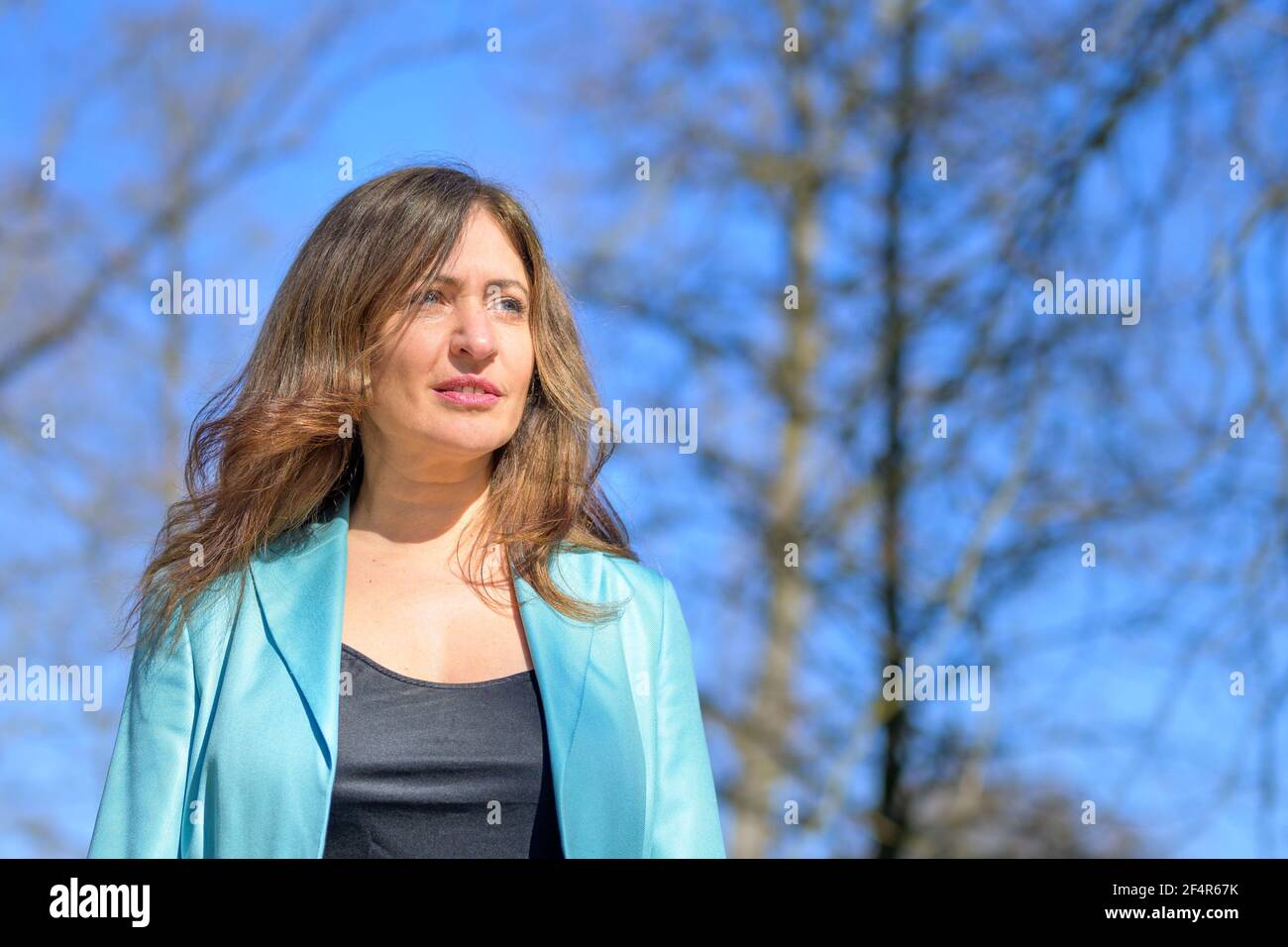 Nahaufnahme eines niedrigen Winkel Porträt einer attraktiven Frau mittleren Alters Wandern im Frühling im Freien gegen einen blauen Himmel und Bäume Mit Blick auf die Zukunft mit einem ernsthaften Ex Stockfoto