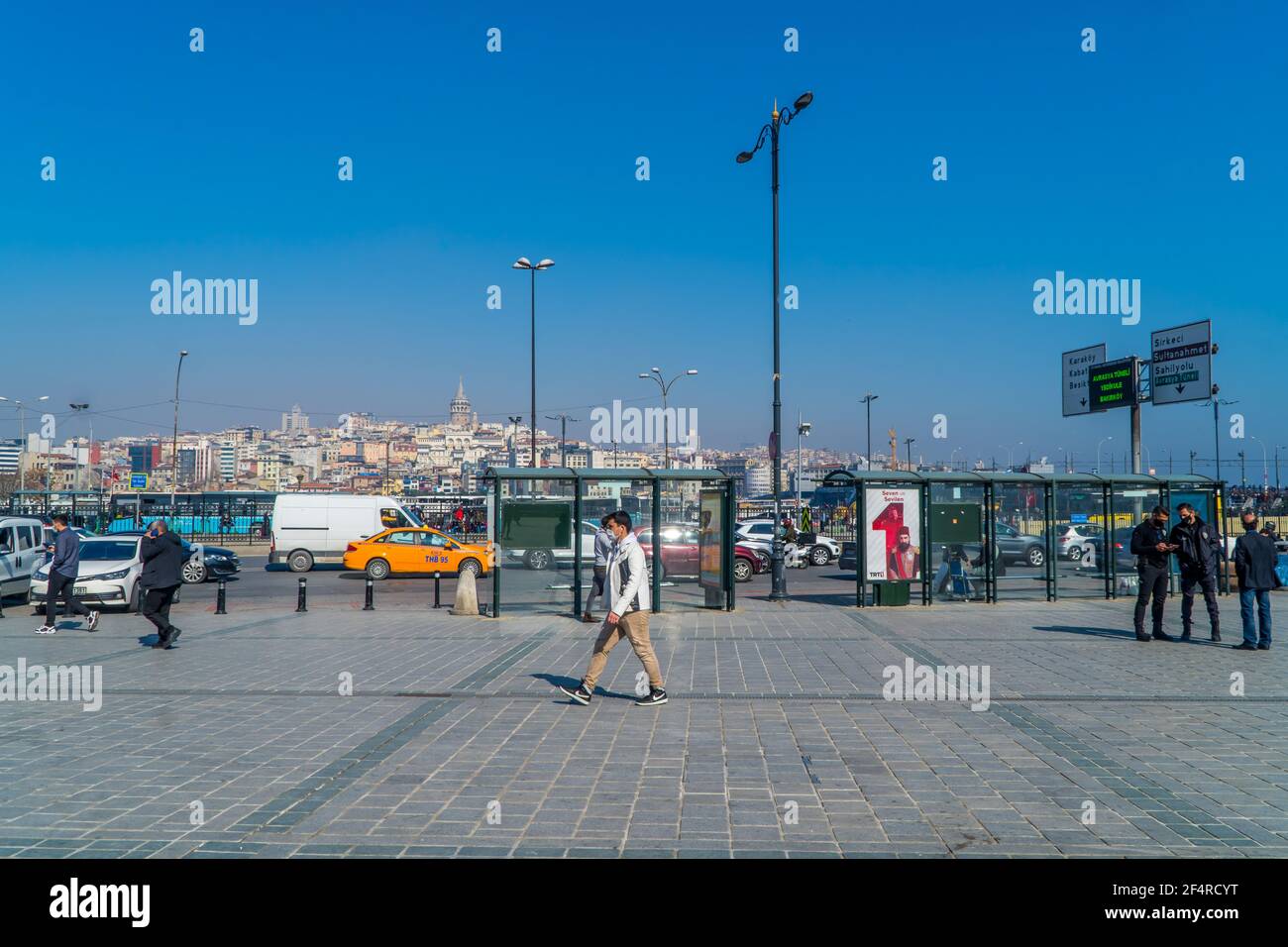Istanbul, Türkei - 23. Februar 2021 - Straßenfotografie von Menschen auf dem Eminönü-Platz mit der Rüstem-Pasa-Moschee an einem sonnigen Tag Stockfoto