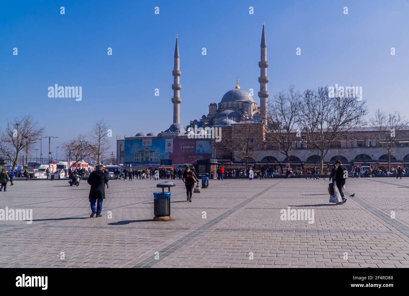 Istanbul, Türkei - 23. Februar 2021 - Straßenfotografie von Menschen auf dem Eminönü-Platz mit der Rüstem-Pasa-Moschee an einem sonnigen Tag Stockfoto