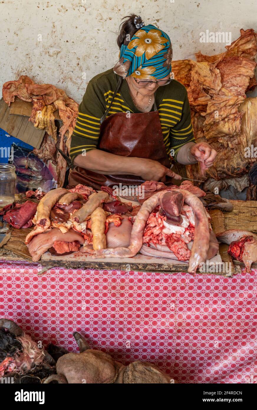 Moron, Mongolei - 13. August 2019: Metzgerin mit mehreren Köpfen von Kühen mit Hörnern liegen auf dem Boden mit Vorbereitung des Fleisches für Kunden in Stockfoto