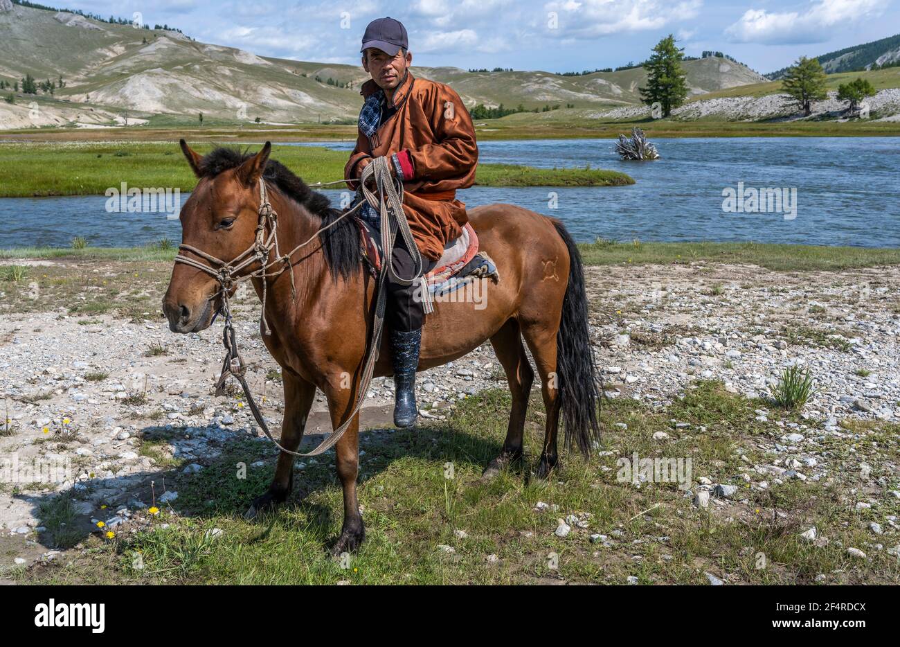 Khatgal, Mongolei - 14. August 2019: Mongolischer Hirte zu Pferd mit Hut und auf der Steppe der Mongolei in der Nähe eines Flusses. Stockfoto