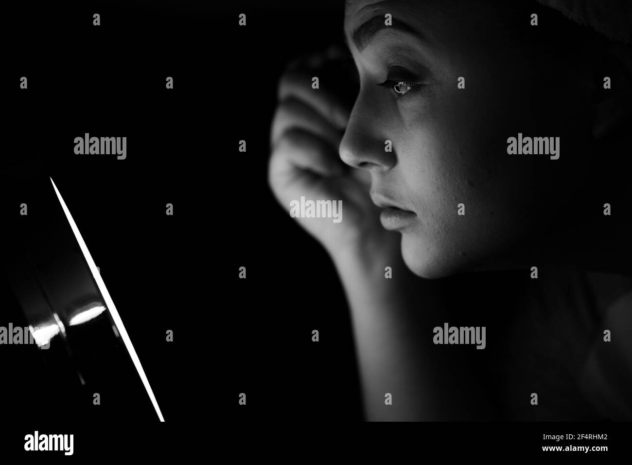 Eine Frau sitzt vor einem kleinen rings beleuchteten Schminkspiegel aus Roségold und trägt Mascara auf. Stockfoto